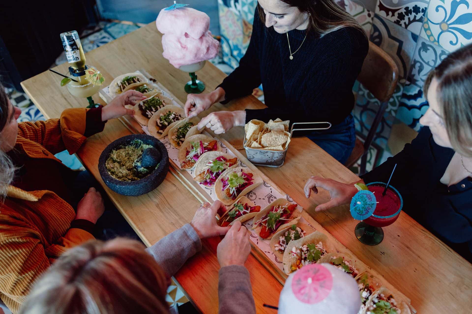 Group of friends digging into a full spread of signature tacos at Camino Taco in the Village.
