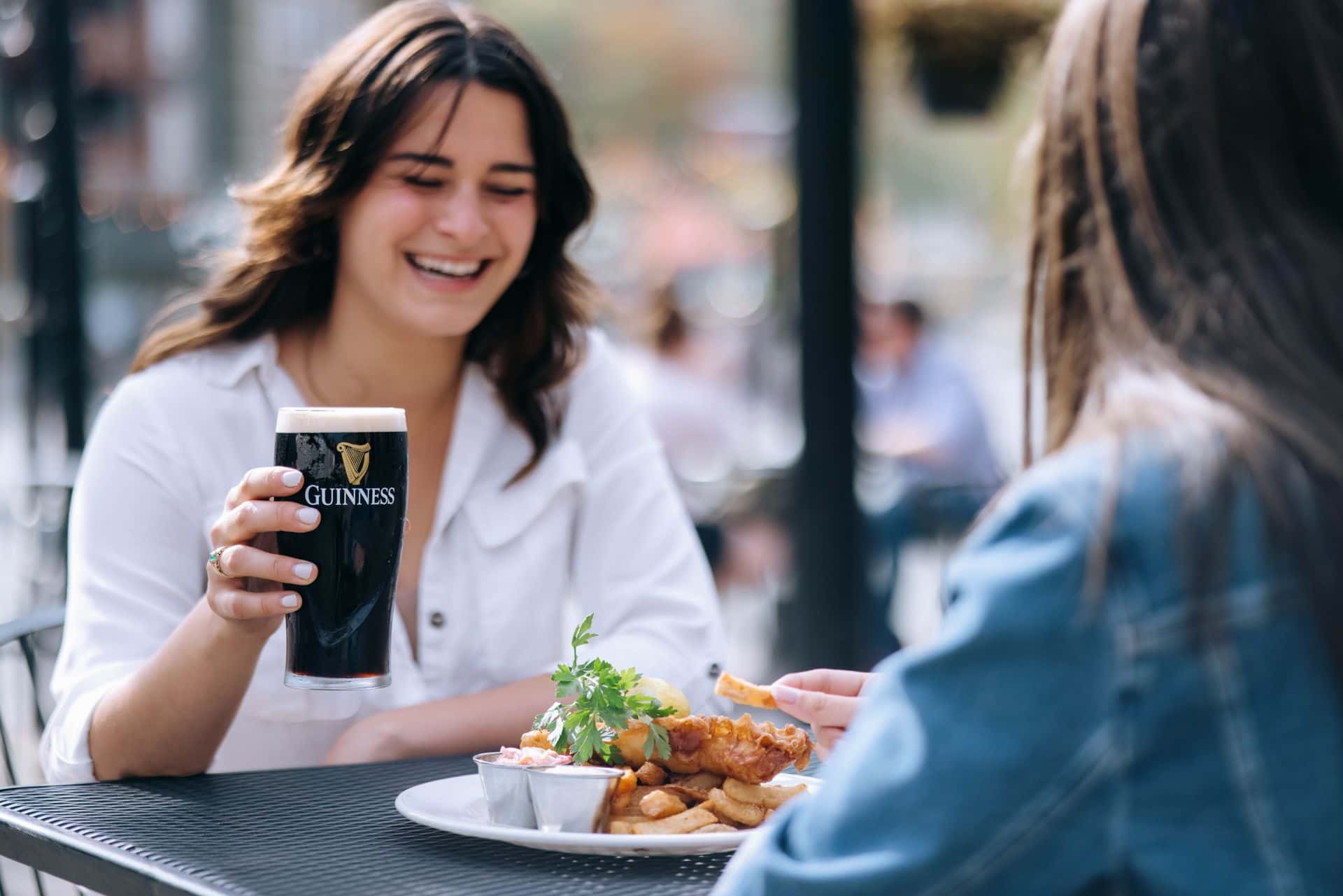 Two friends dining on MJ Byrne's outdoor patio, sipping a pint of Guiness of course!