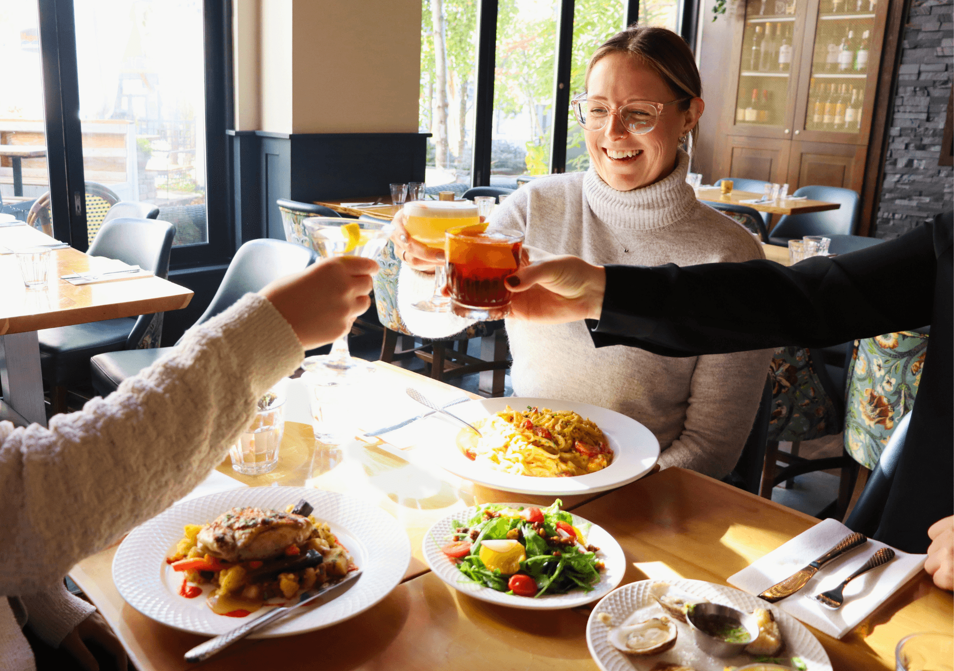 Group of girls cheersing their cocktails while dining at Twist Kitchen + Cocktail