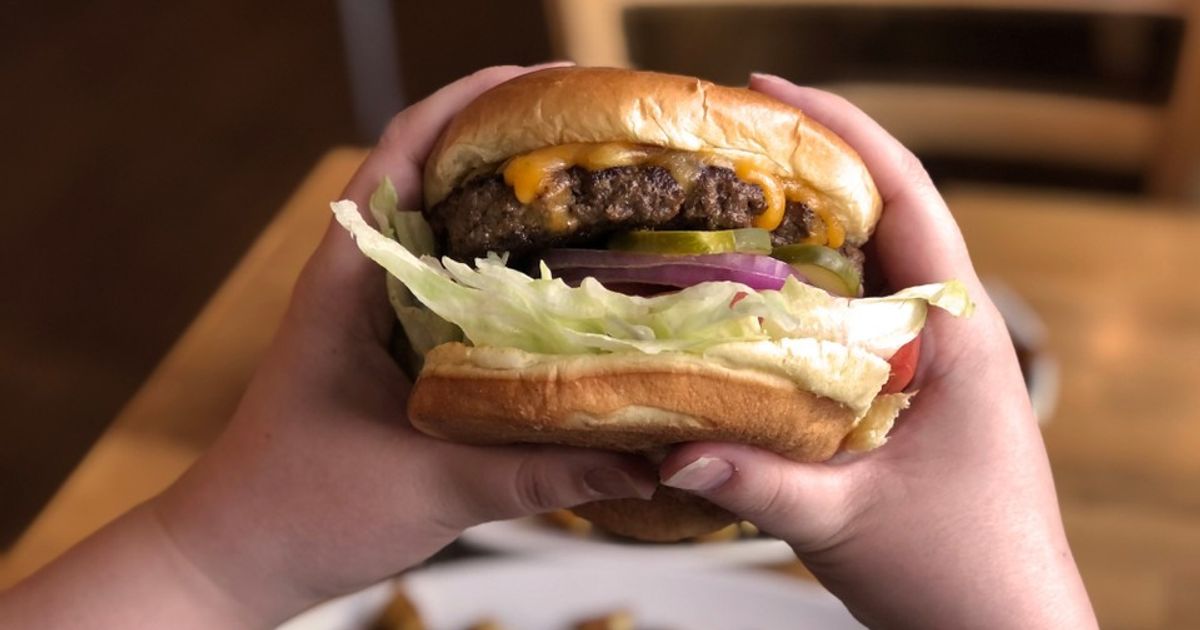 POV of holding up a juicy hamburger for lunch at Sunset Grill