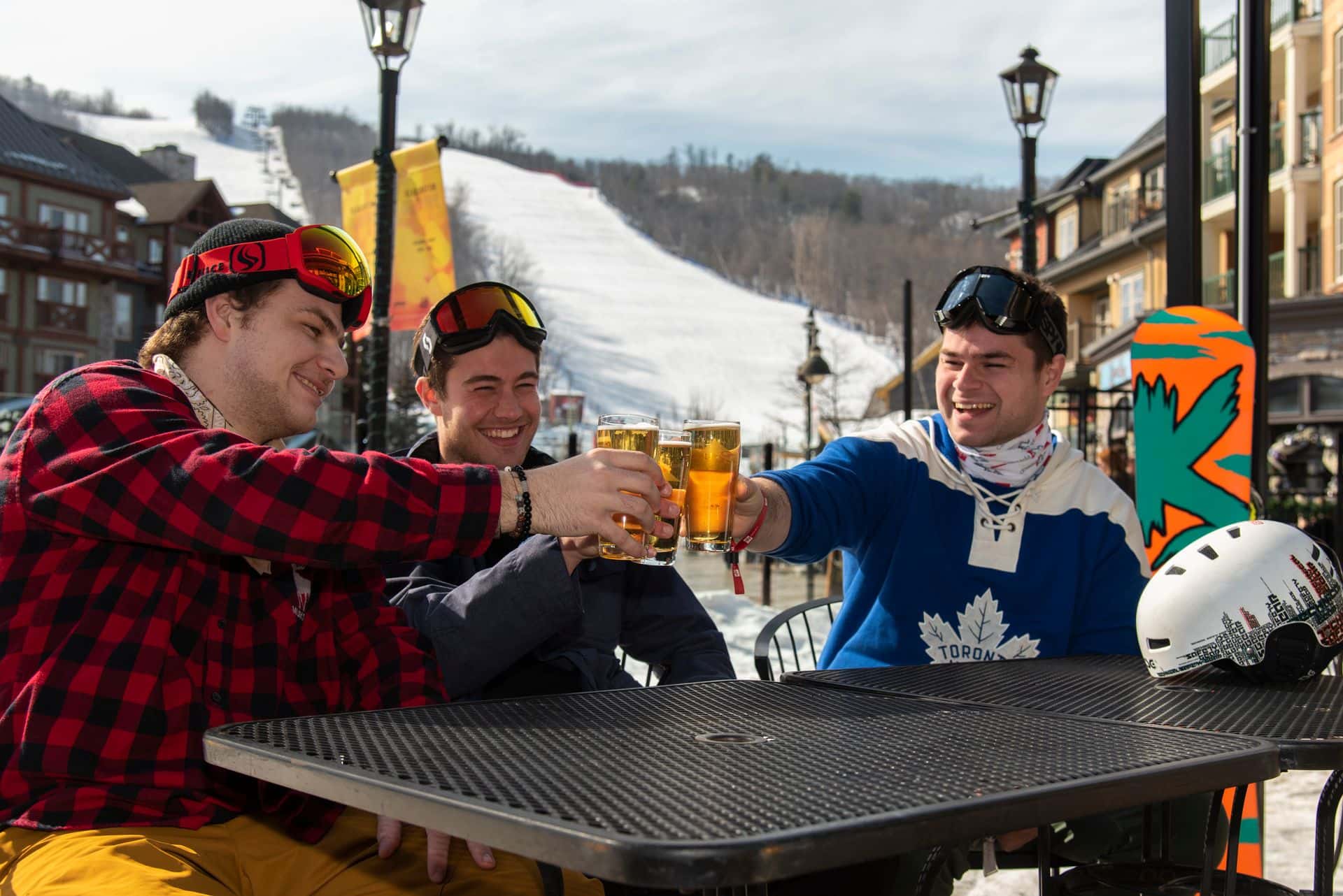 3 buddies cheers their beers together on the heated patio at MJ Byrne's Irish Pub after a day of snowboarding.