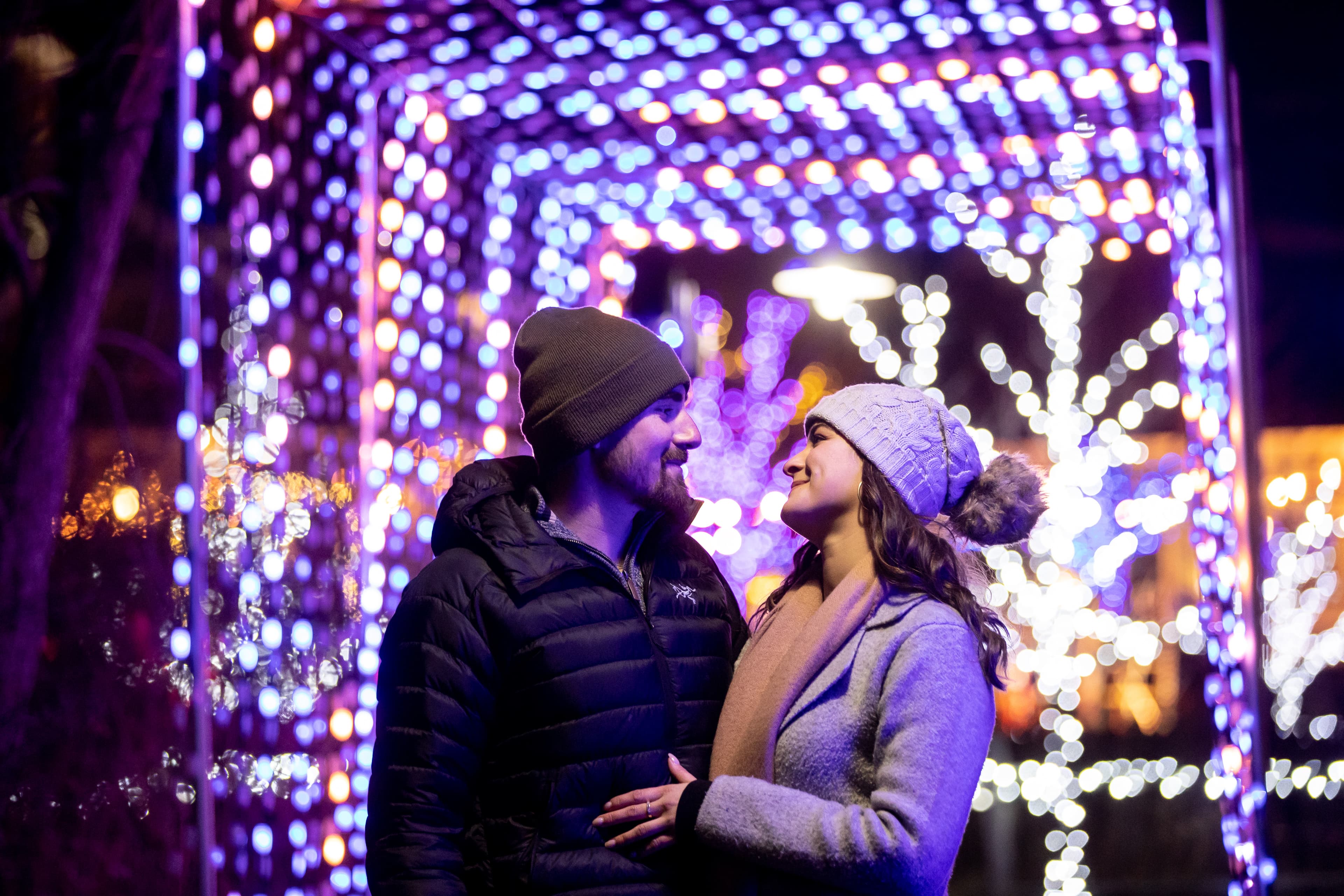 Young couple embracing beneath the glowing Holiday Magic Lights