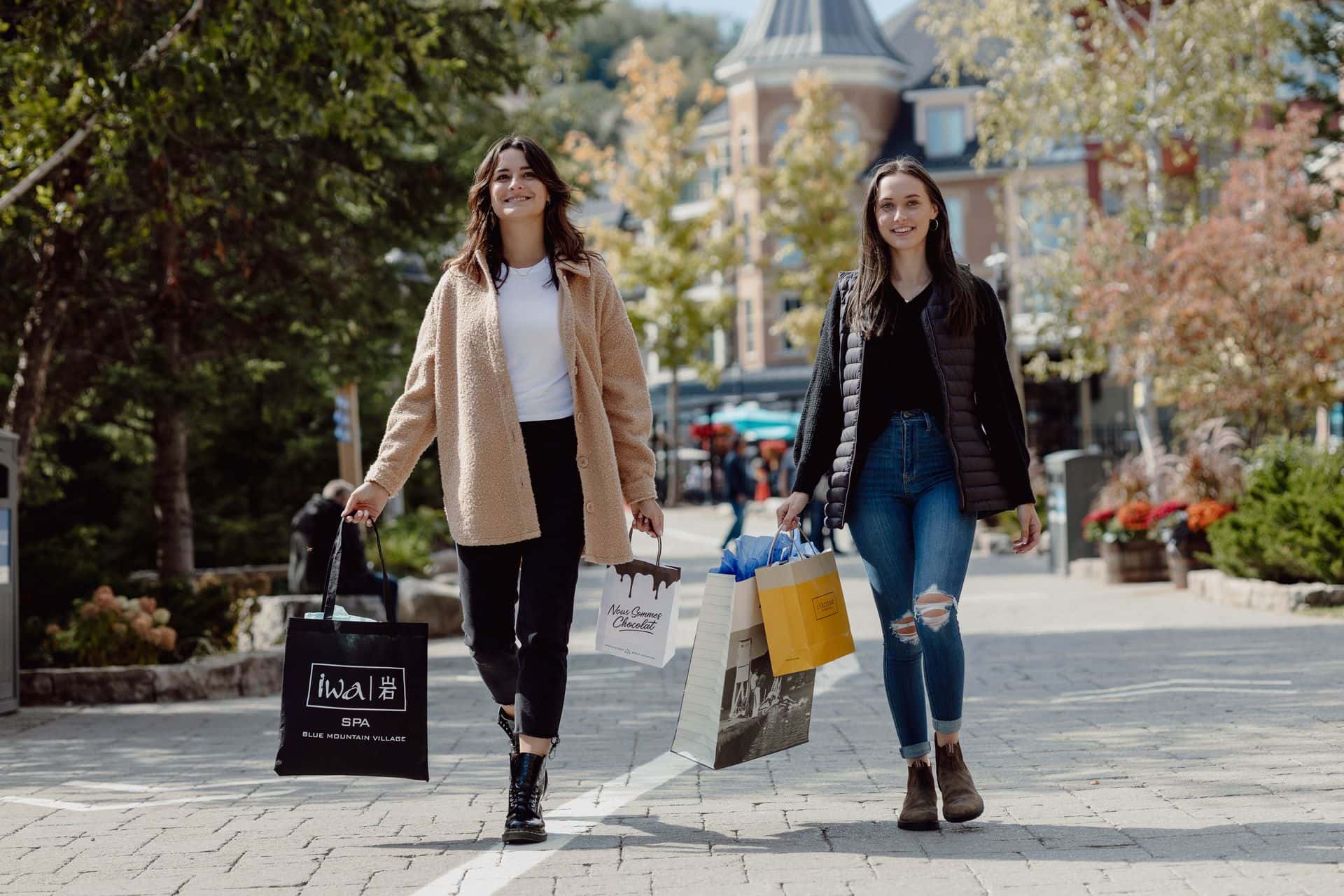 Two friends walking through the village with shopping bags on a sunny day.