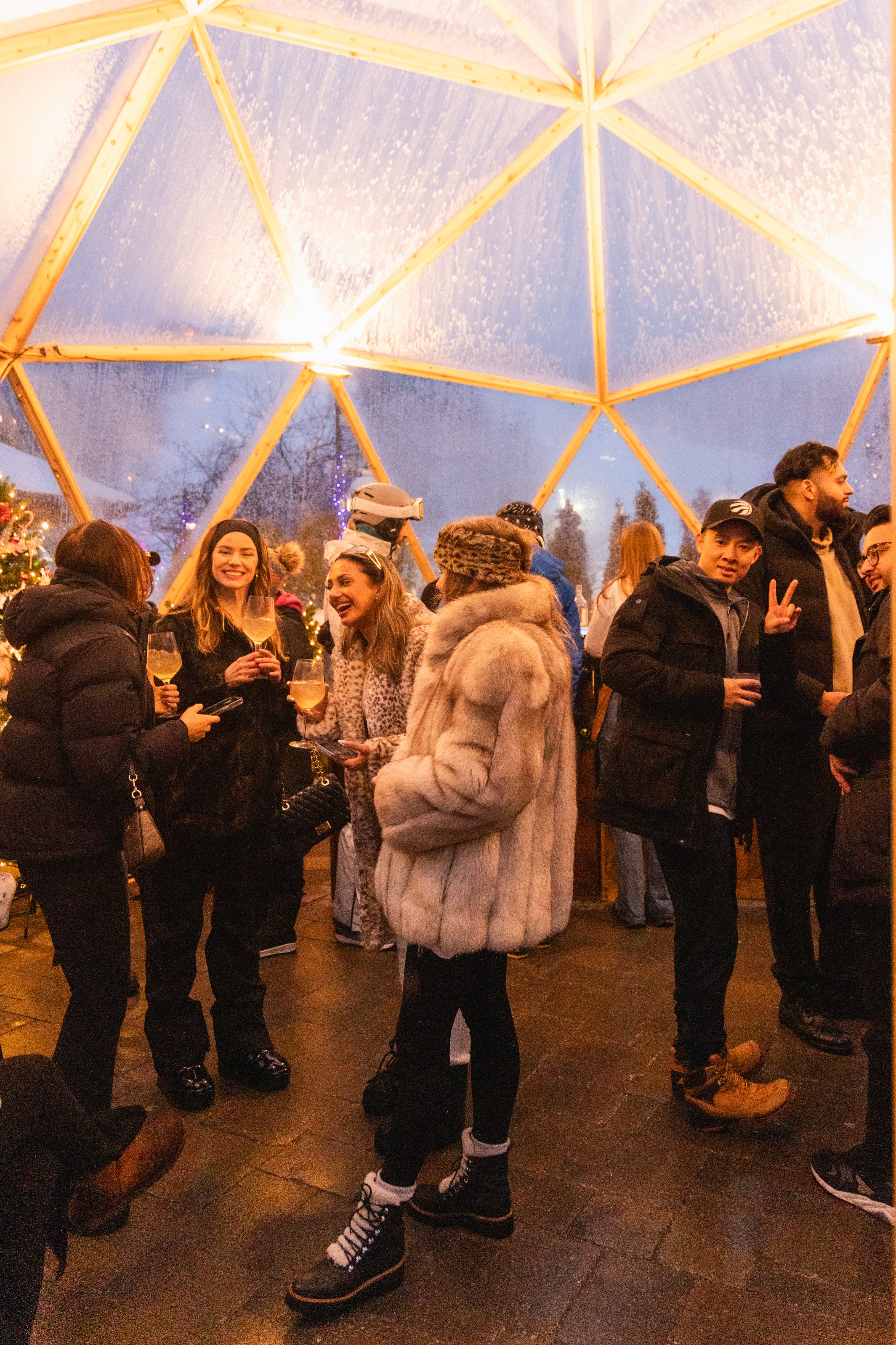 Large friend group of young adults wearing fur coats and traditional Après wear inside the Snowdome Cocktail Bar