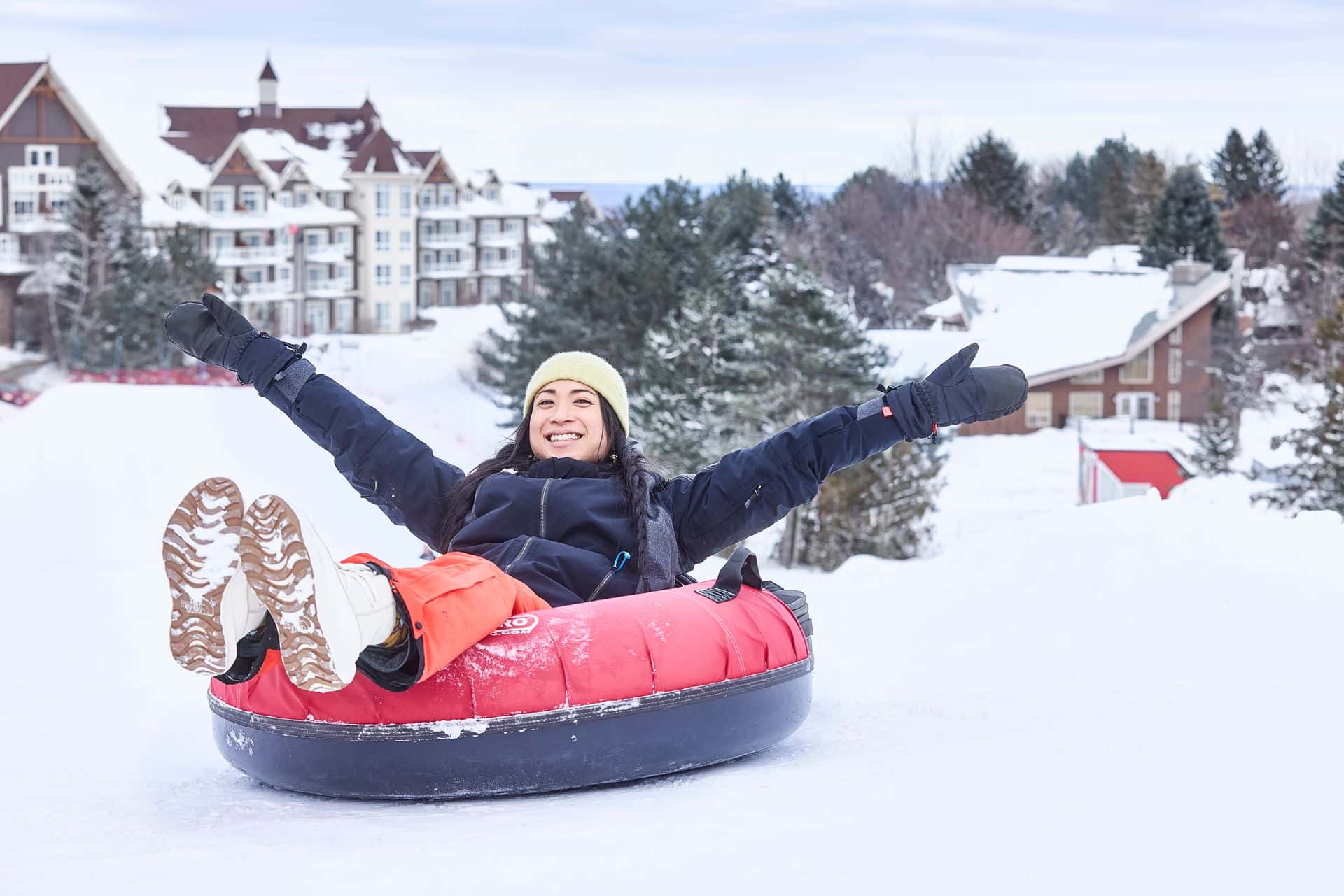 A woman sitting in a tube at the top of the Blue Mountain Resort Tube Park with her hands in the air.