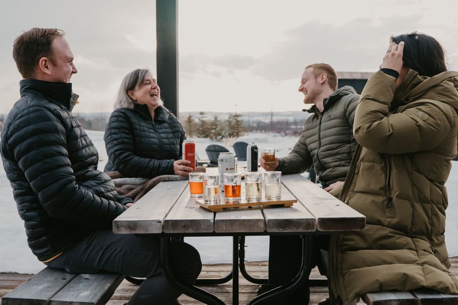 Group of friends laughing over cider flights at Spy Cider House and Distillery, part of the Apple Pie Trail.