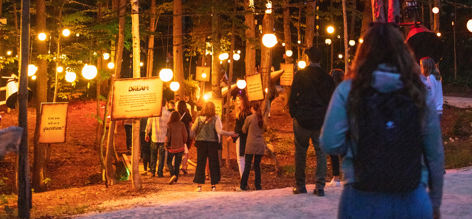 A group of guests walking through the illuminated mountaintop trail on a Fall evening for AGORA Path of Light