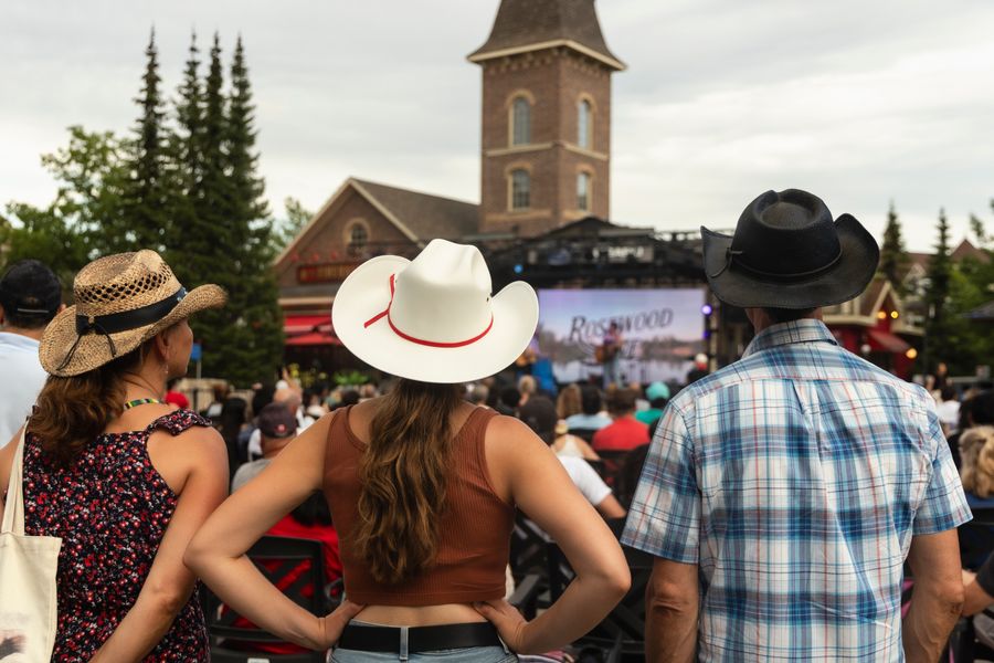 A family stands in cowboy hats to watch a performance at CountryFest.
