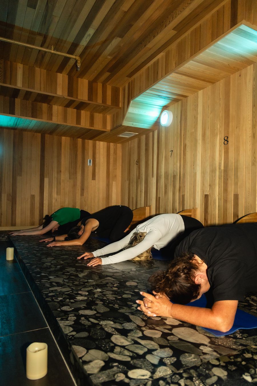 Group of women in balasana yoga pose in iwa Spa's heated Volcanic rock room.