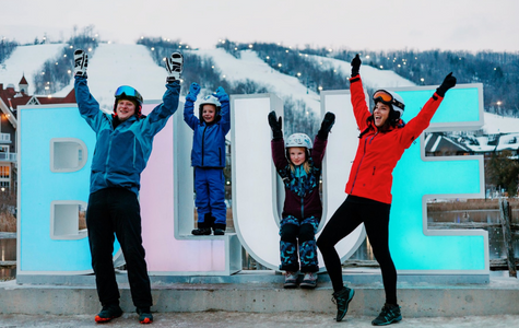 Family dressed in warm winter wear celebrate the Winter at Blue Mountain Village